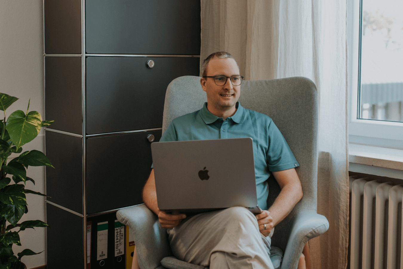 Lukas Leitner sitzt in seinem Beahndlungszimmer und hat einen Laptop auf dem Schoß.